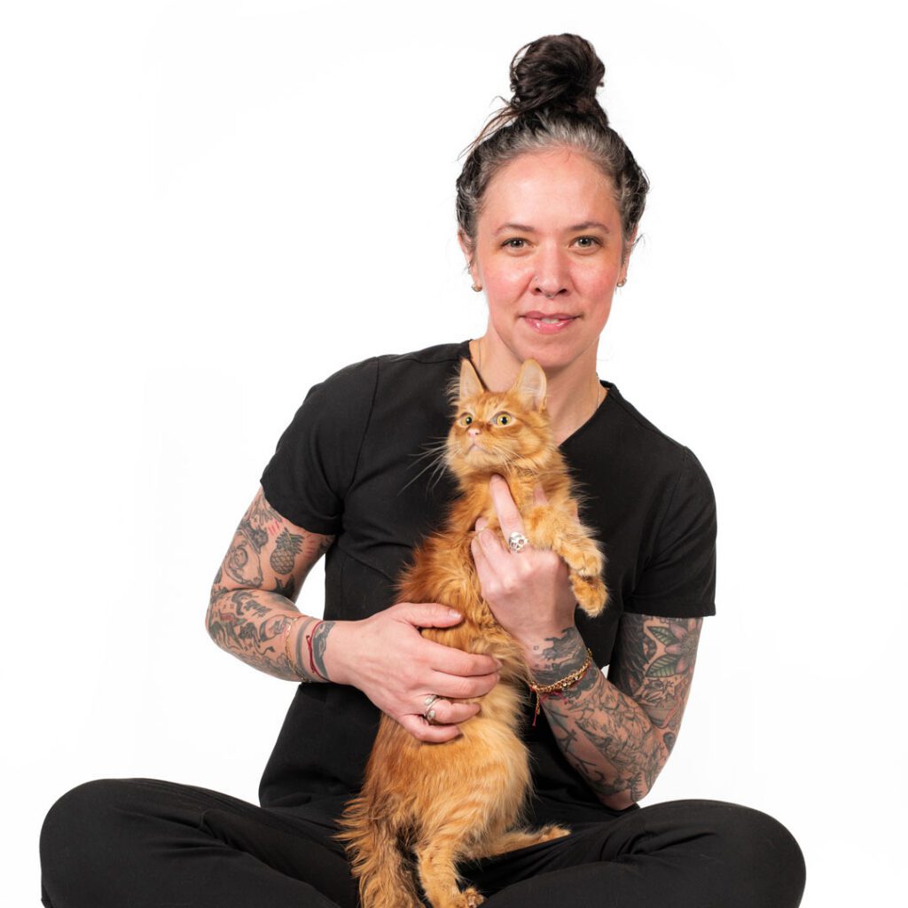 smiling woman with tattoos holding an orange cat