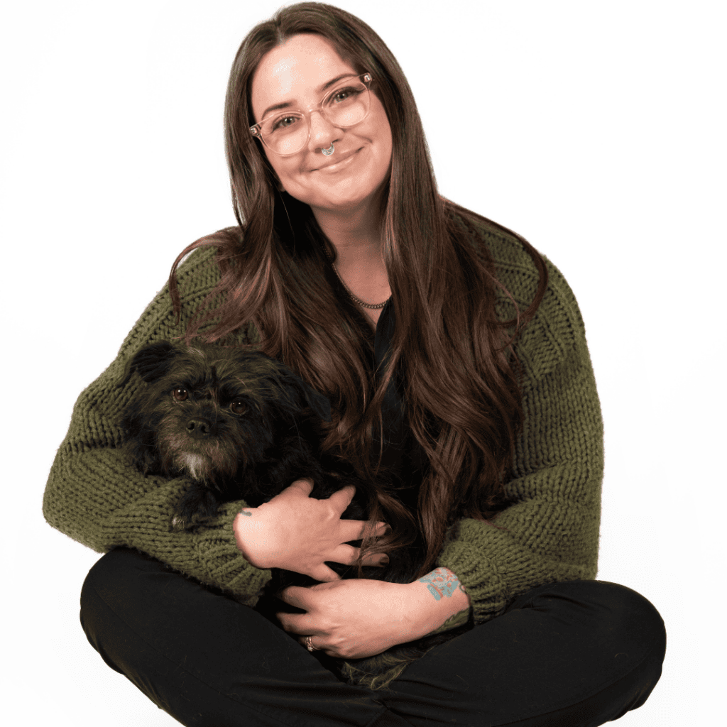 Jenn Hughes smiling and holding a black dog